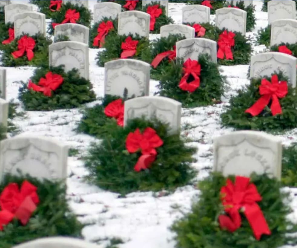 Photo of a Veteran Cemetery with snow on the ground and wreaths with red bows at every gravesite.