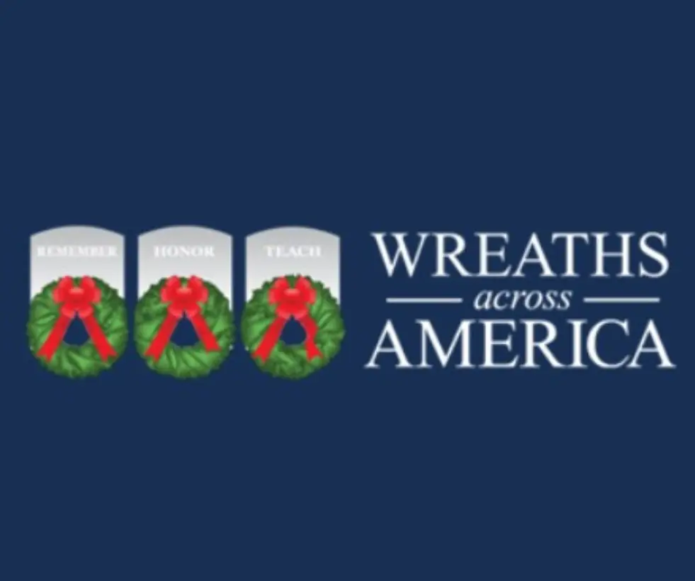 Photo of Wreaths Across America logo, which has the words and three gray heard stones with green wreathes with red bows on the wreaths.